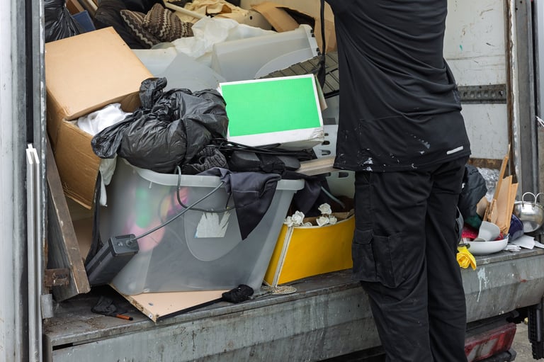 Worker unloading mixed waste, household items, and rubbish
